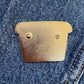 Brass label on a denim fabric with 'Happy Little Paper Co.' branding.