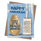 A square greeting card with a kraft envelope behind it, featuring a light blue distressed background, a brown potato illustration, and a cream-colored grater. The text reads 'HAPPY HANUKKAH!' at the top and 'I HOPE IT'S REALLY GRATE.