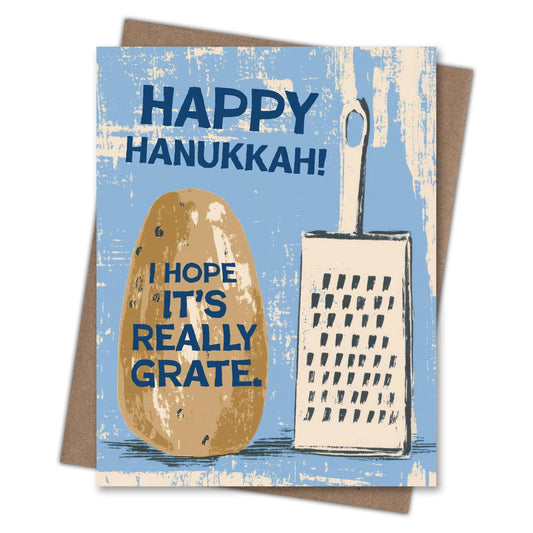 A square greeting card with a kraft envelope behind it, featuring a light blue distressed background, a brown potato illustration, and a cream-colored grater. The text reads 'HAPPY HANUKKAH!' at the top and 'I HOPE IT'S REALLY GRATE.