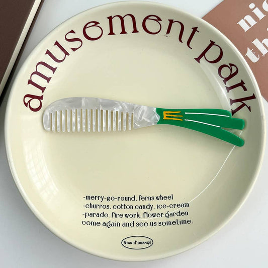 Decorative plate with a comb that looks like a green onion on a white background