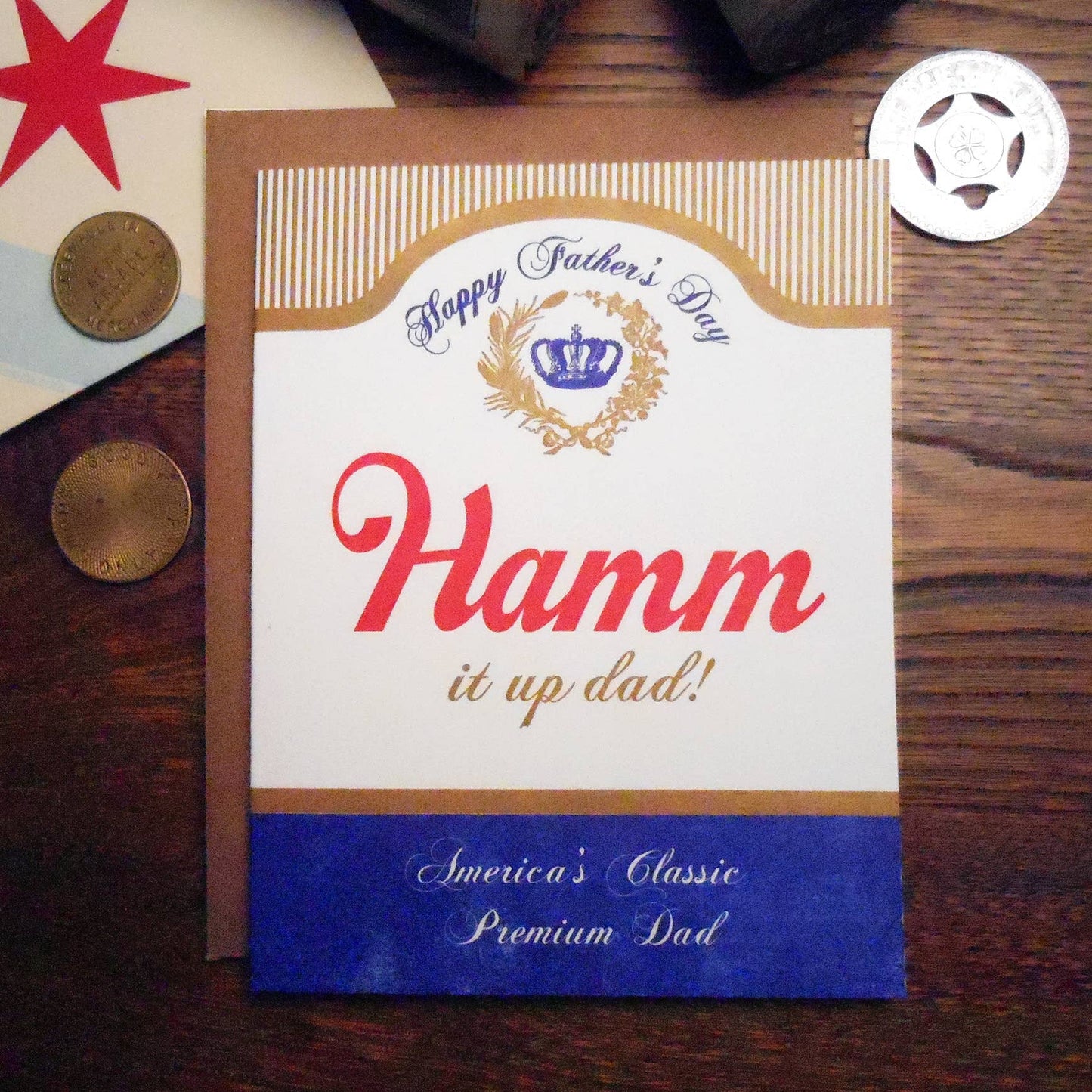 Greeting card with 'Happy Father's Day' and 'Hamm it up dad!' text on a wooden surface.