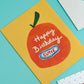 Birthday card with an orange design and 'Happy Birthday Cutie' text on a yellow background, placed on a turquoise surface.