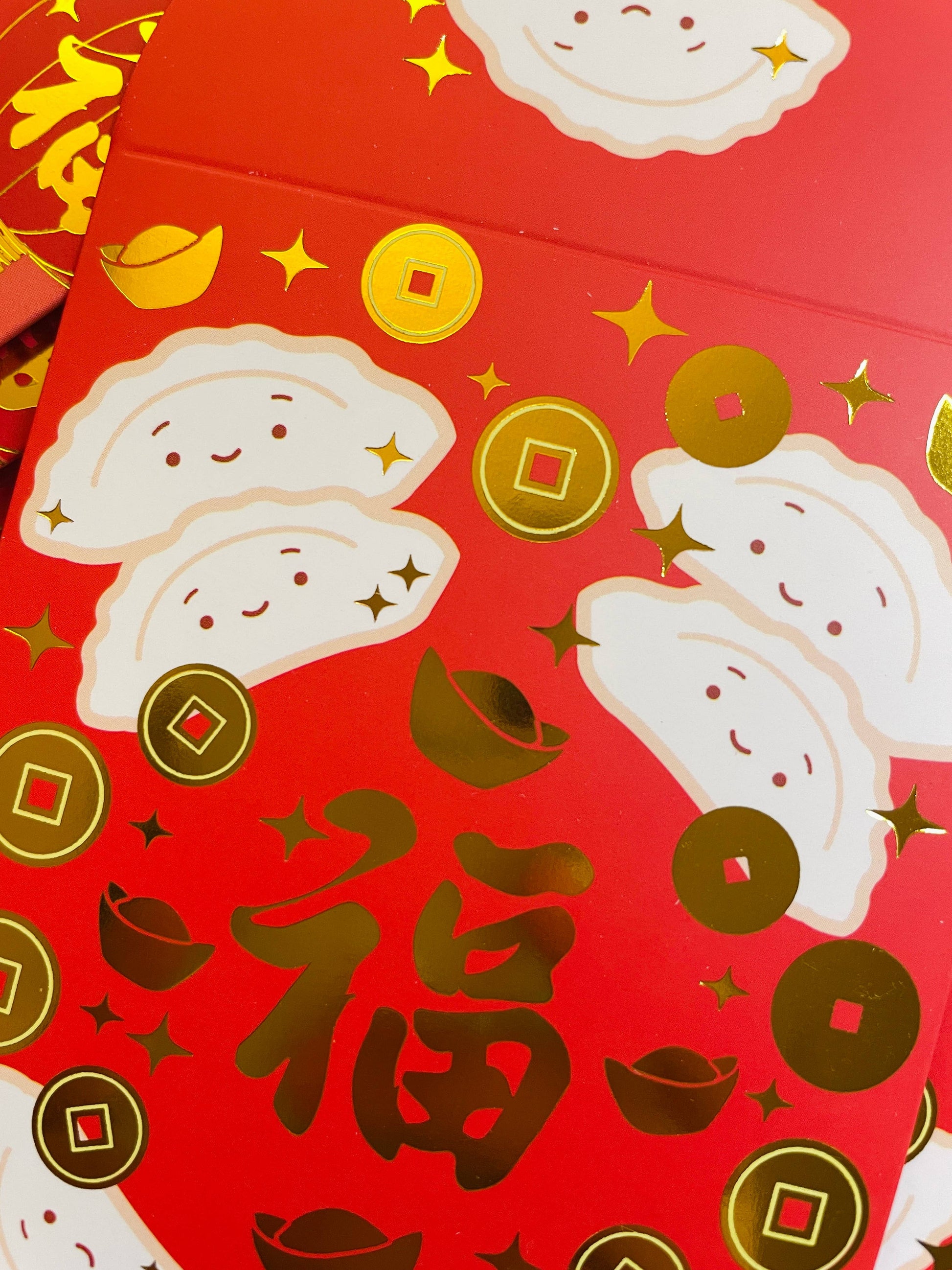 close up of gold foiled red envelopes with happy dumplings on them 