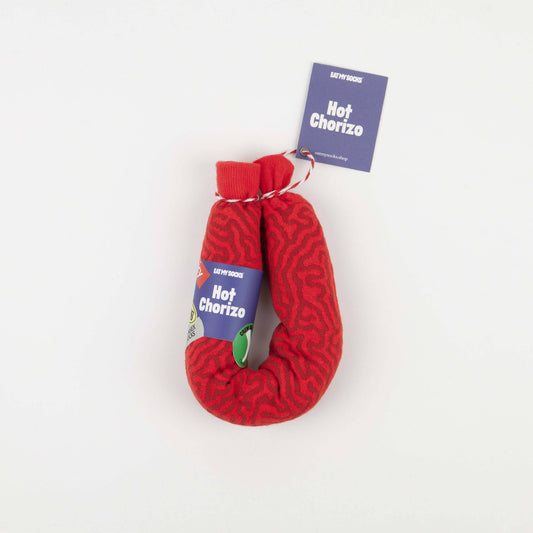 A red textured sock shaped like a hot chorizo link, with a blue tag that reads 'SPITFIRE Hot Chorizo' attached, photographed on a plain white background.