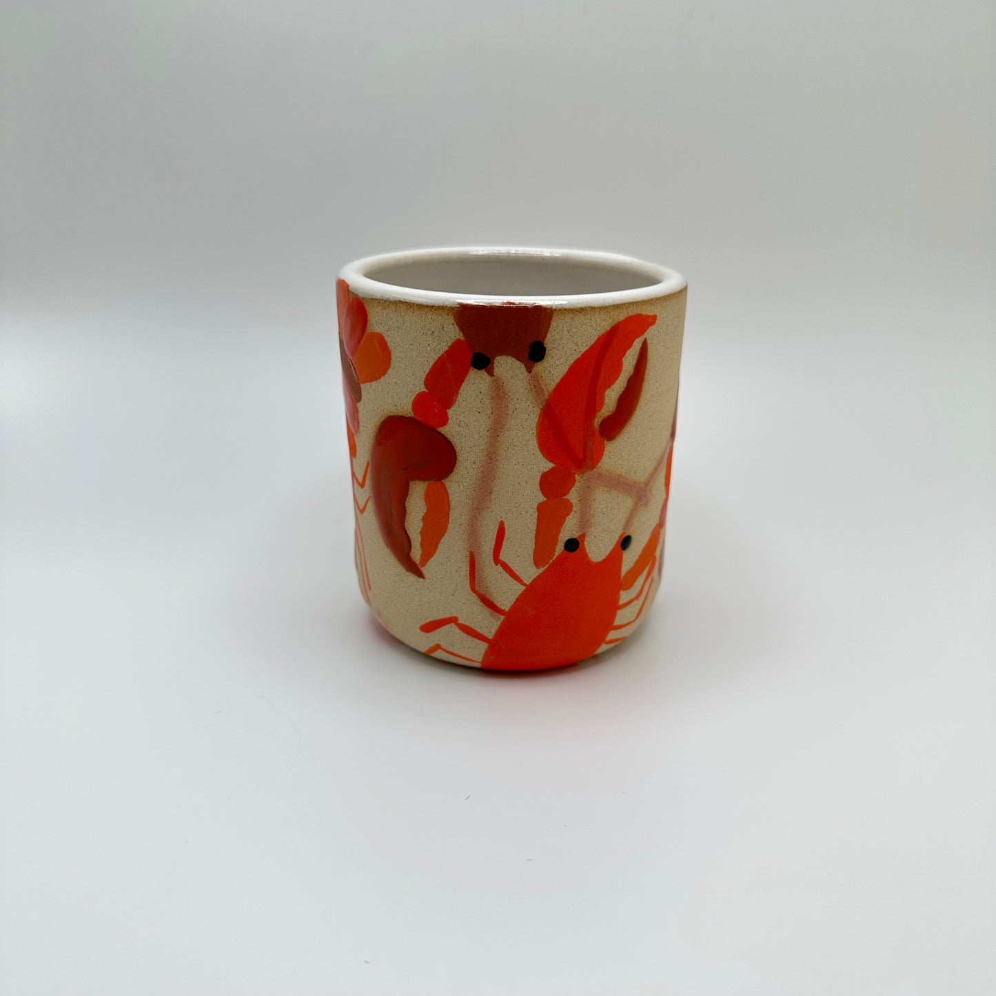 Ceramic tumbler with hand painted lobsters all around the cup. 
