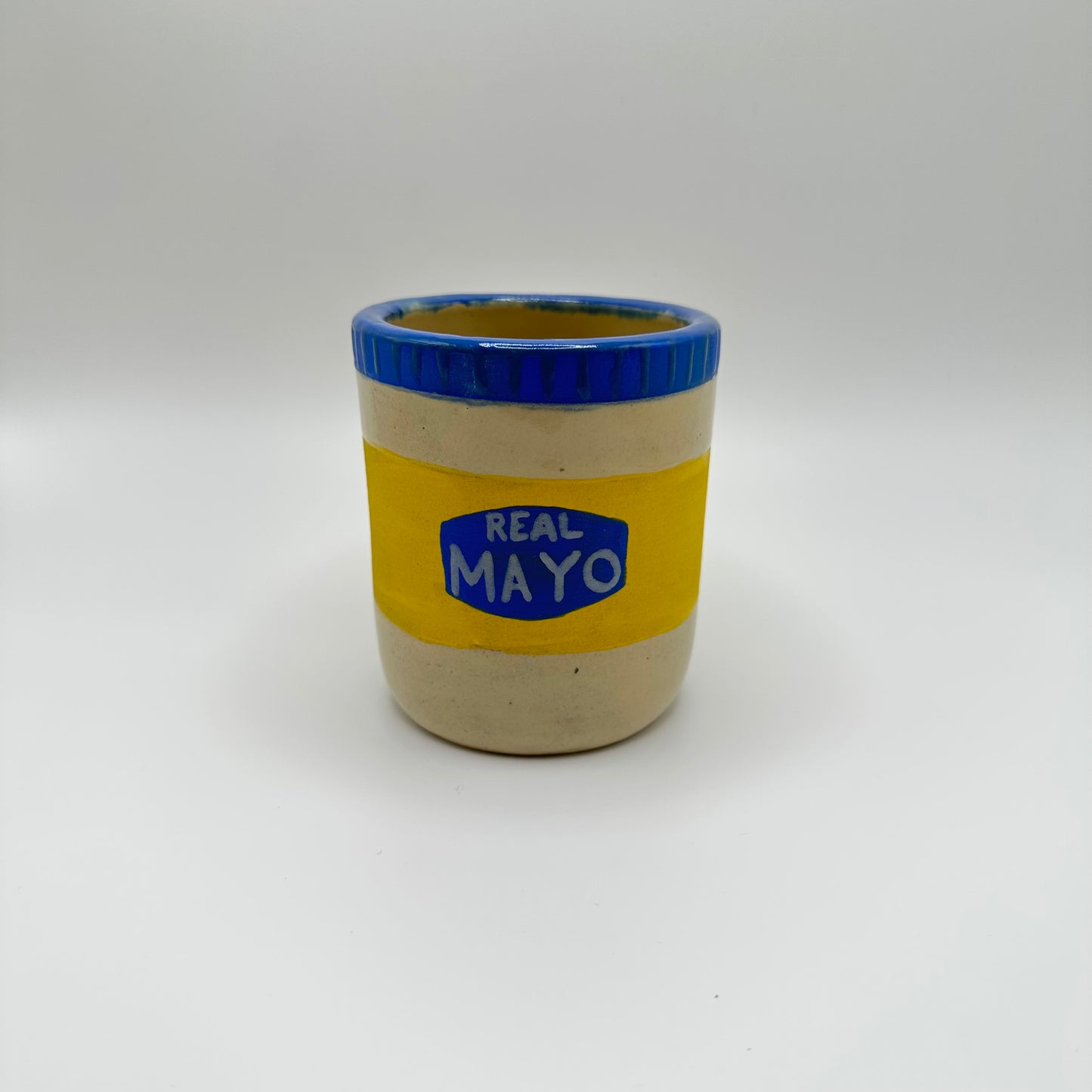 Ceramic tumbler hand painted to look like a jar of "Real May" with a blue lid.