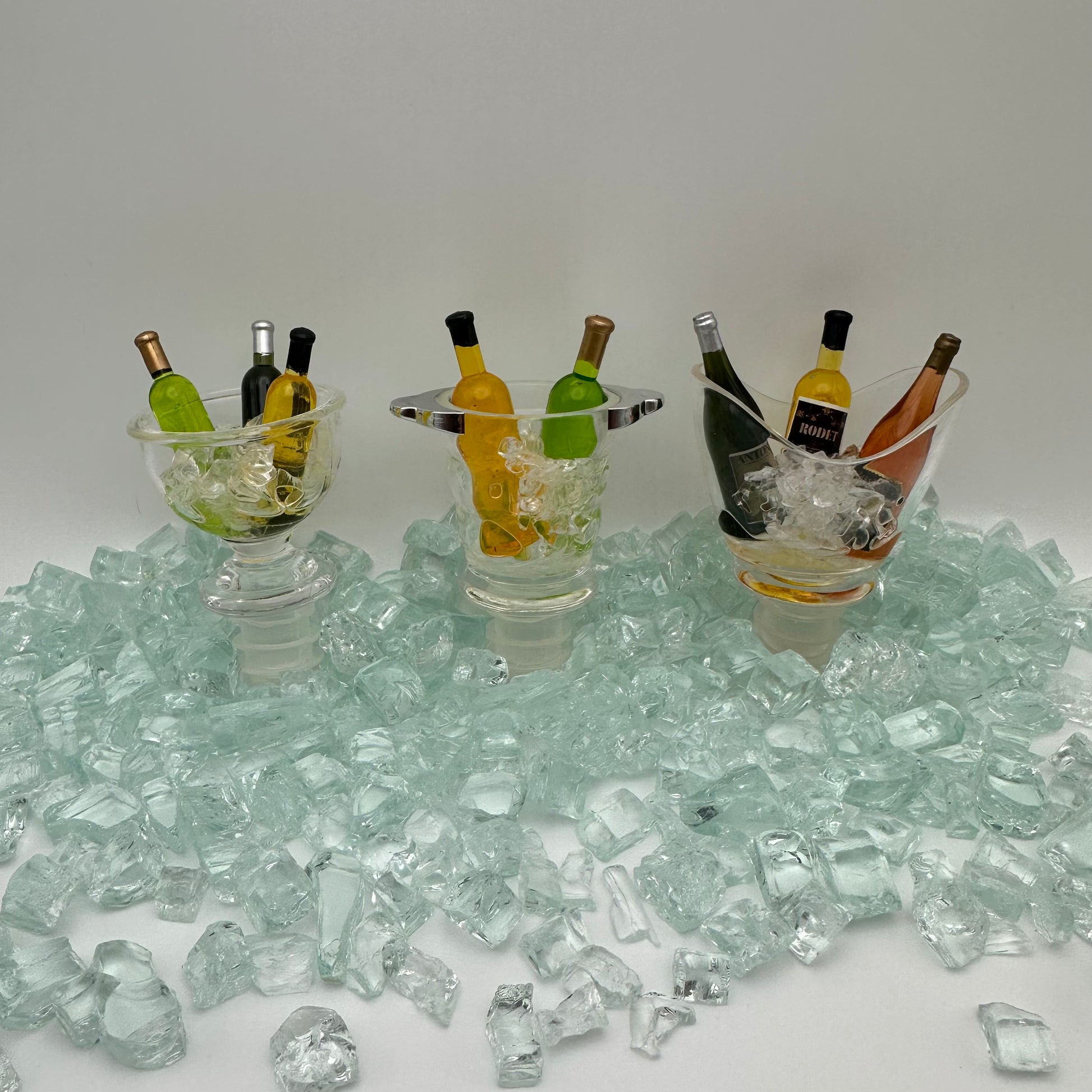 3 Bottle stoppers designed with various acrylic wine bowl shapes filled with mini fake ice and 3 wine bottles in it. 
