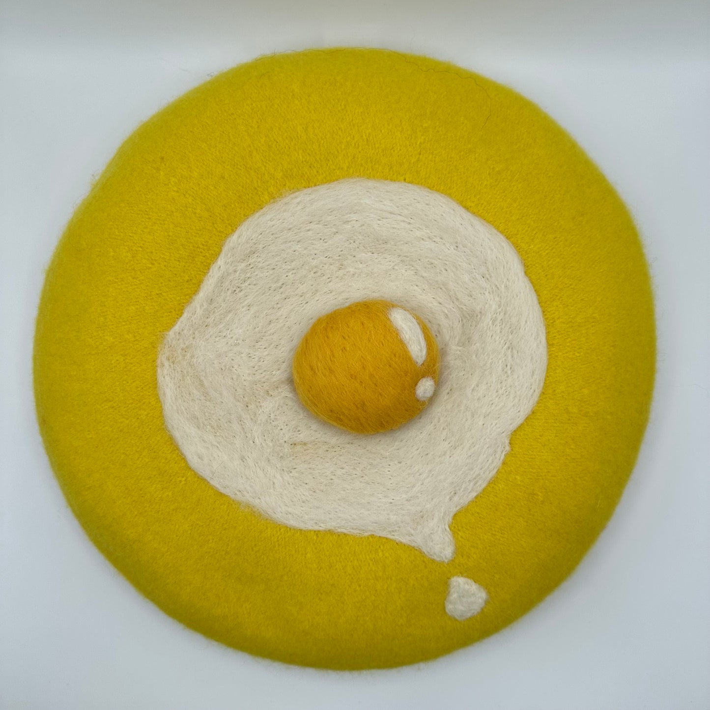 Yellow beret with sunny side up drippy egg.