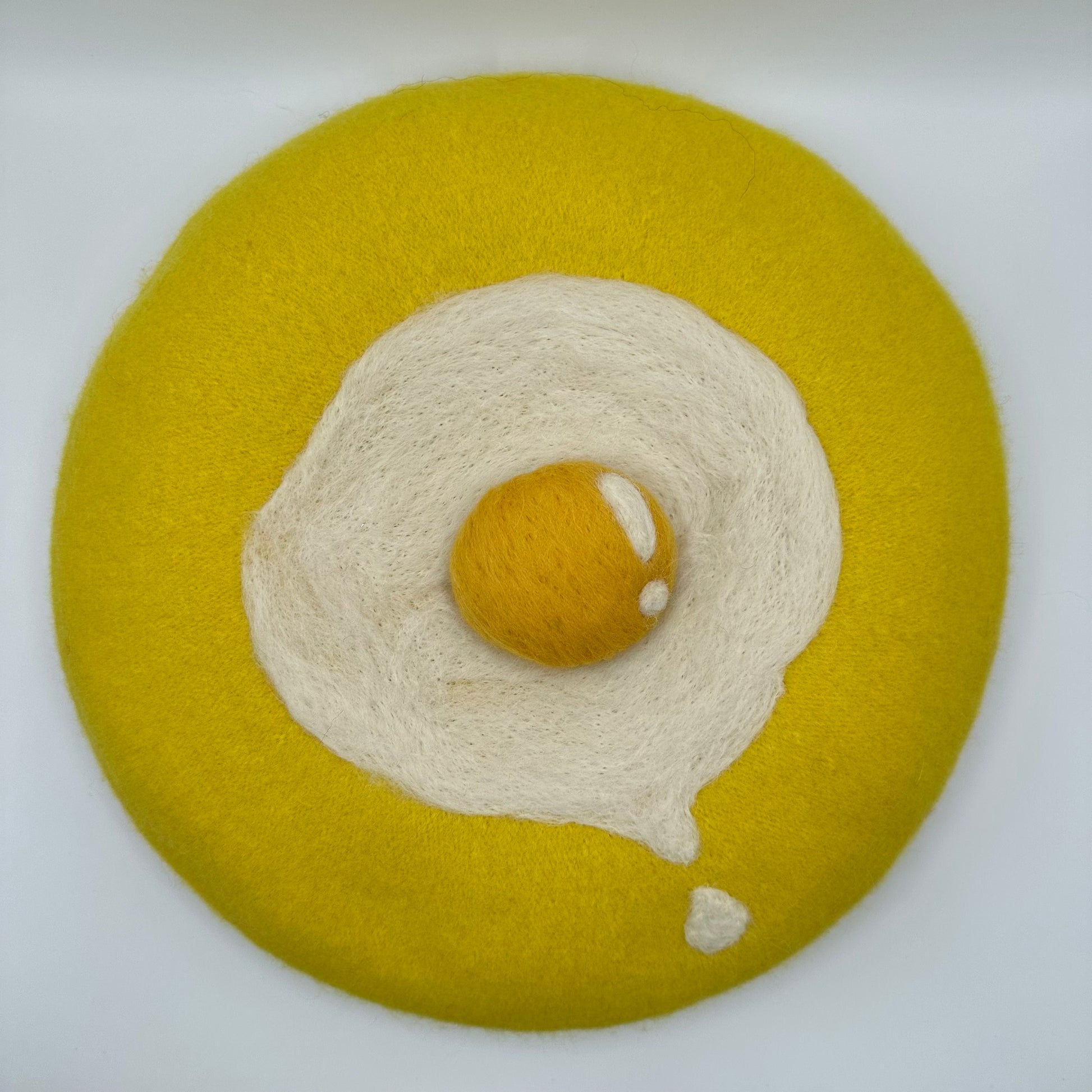 Yellow beret with sunny side up drippy egg.