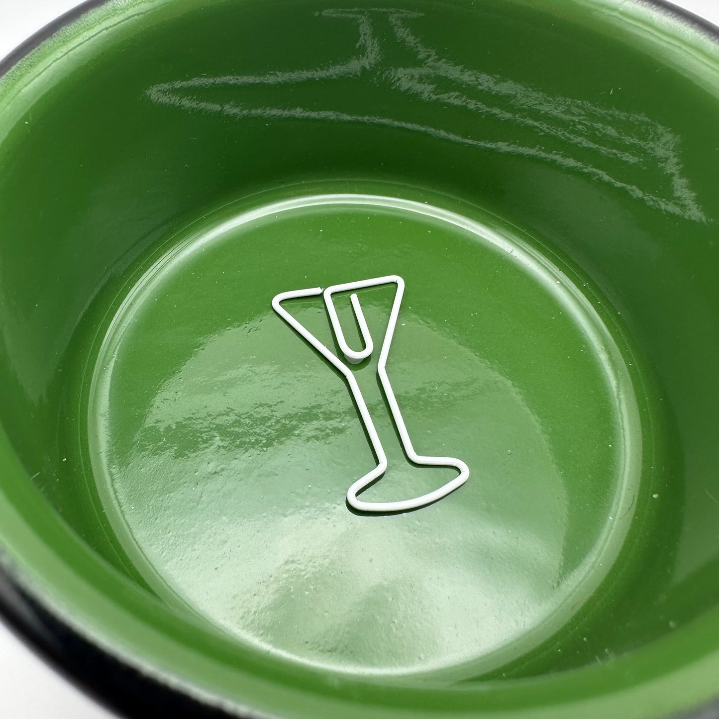 Single white martini paperclip in a green ramekin.