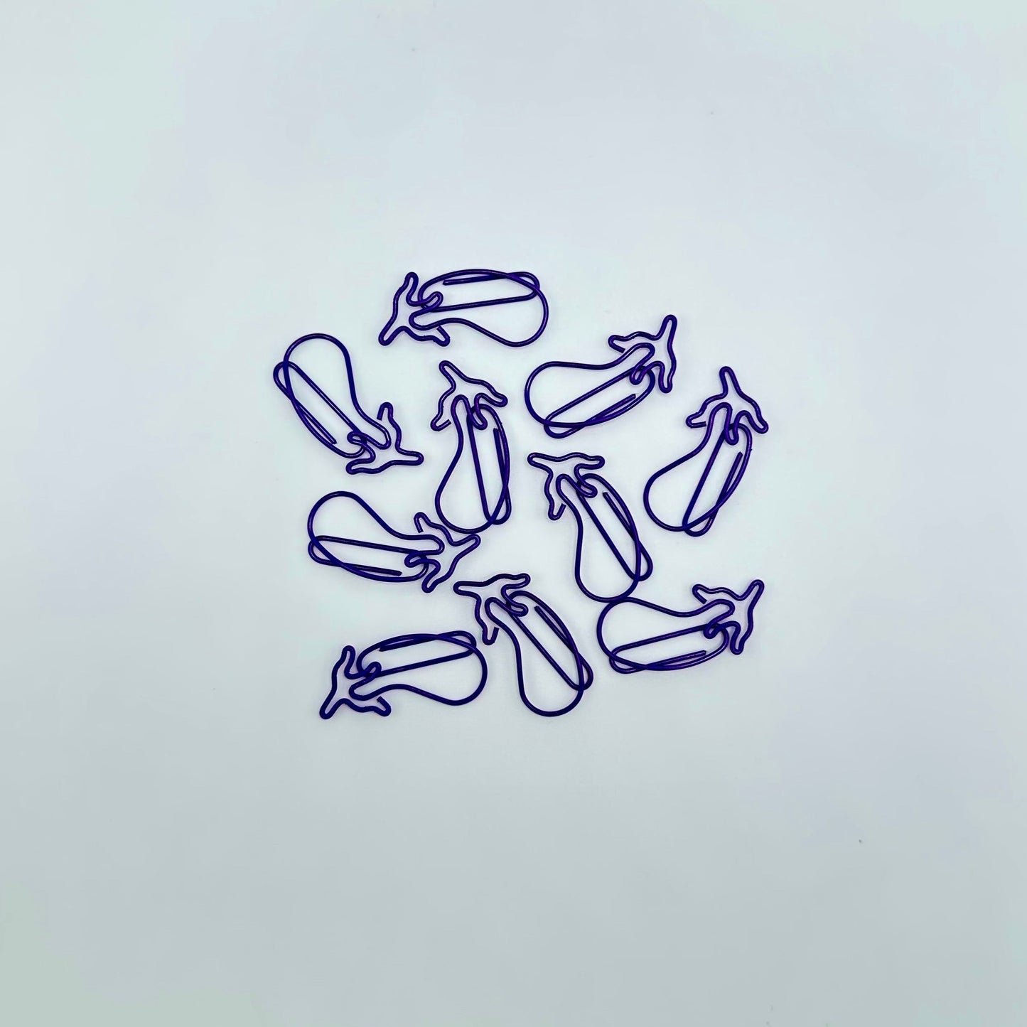 Pile of eggplant shaped, purple paperclips