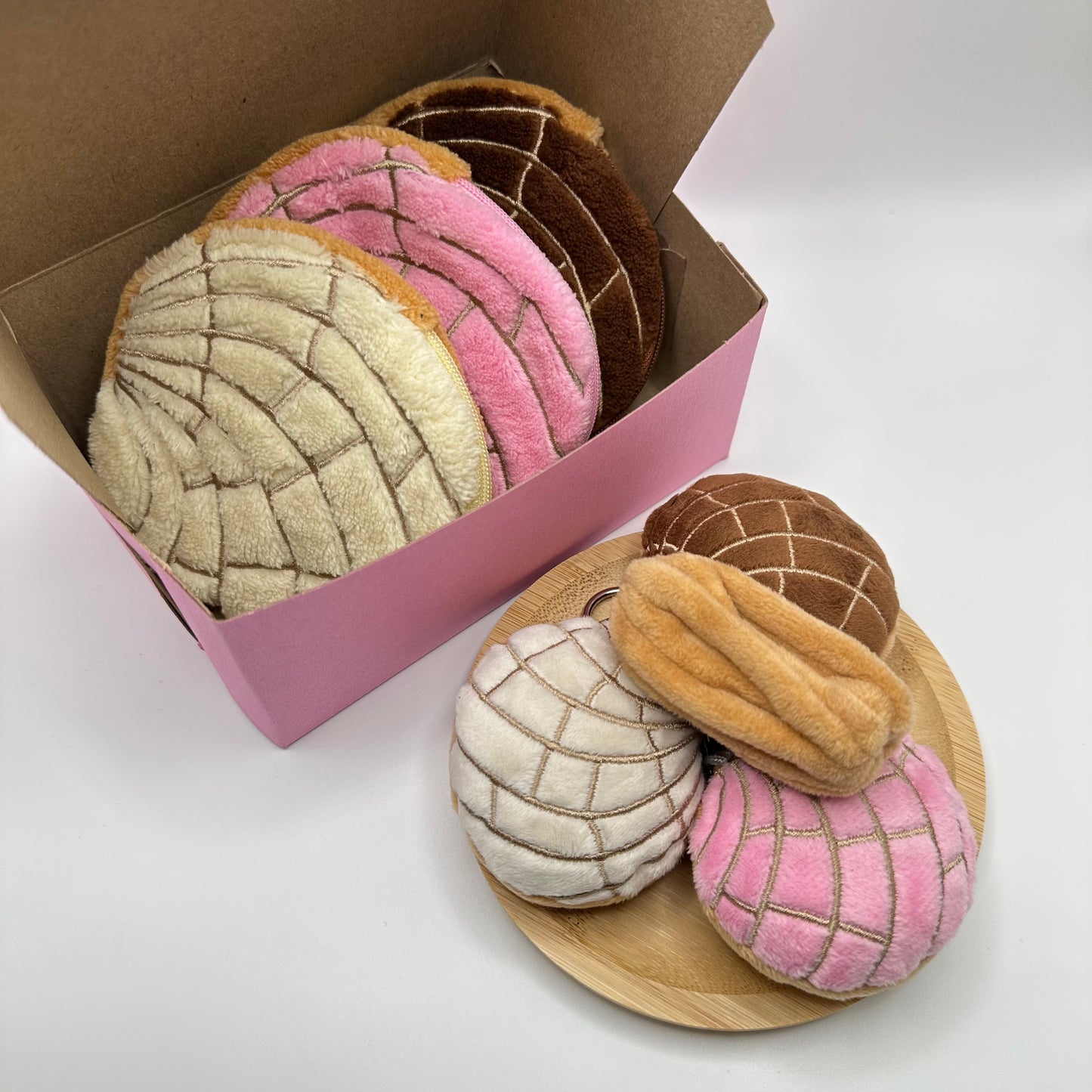 Mexican pastries in the form of pouches and keychains displayed in a pink pastry box and plate.