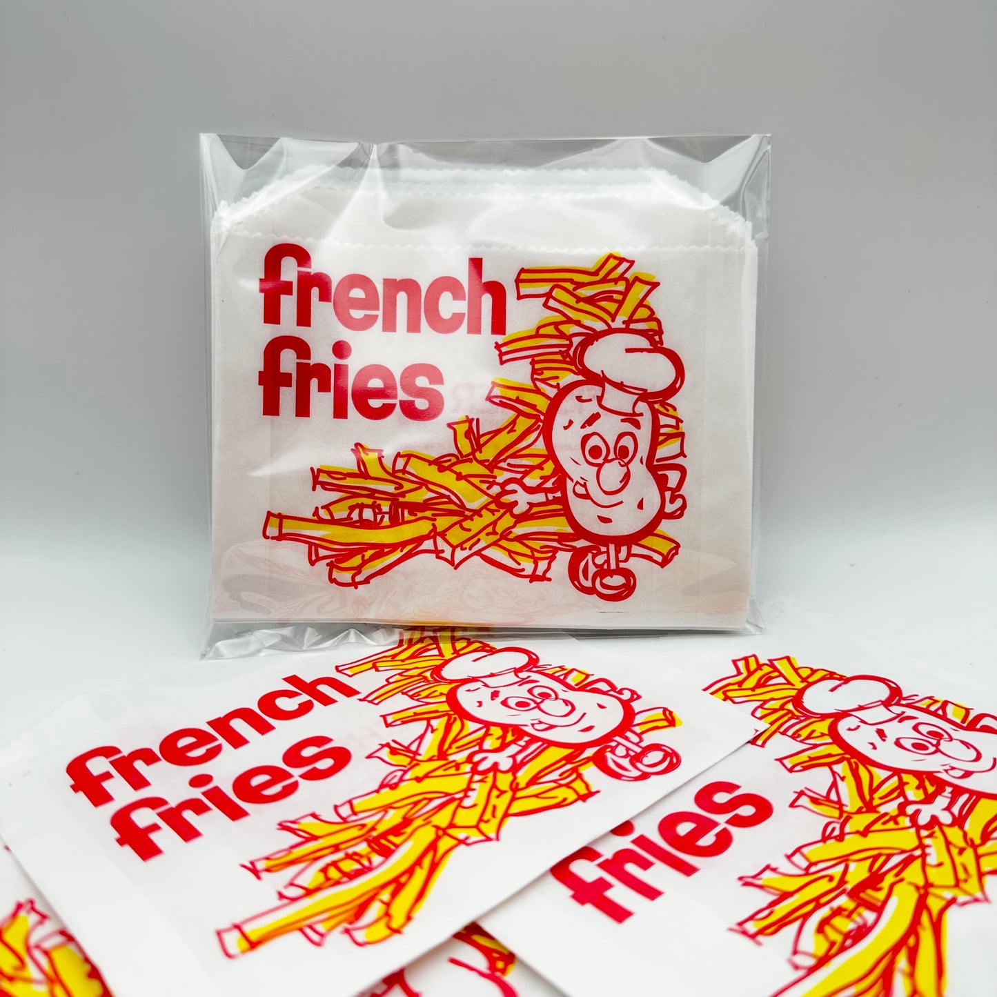 French Fries bag with a potato wearing a chef's gat standing in front of a pile of fries.