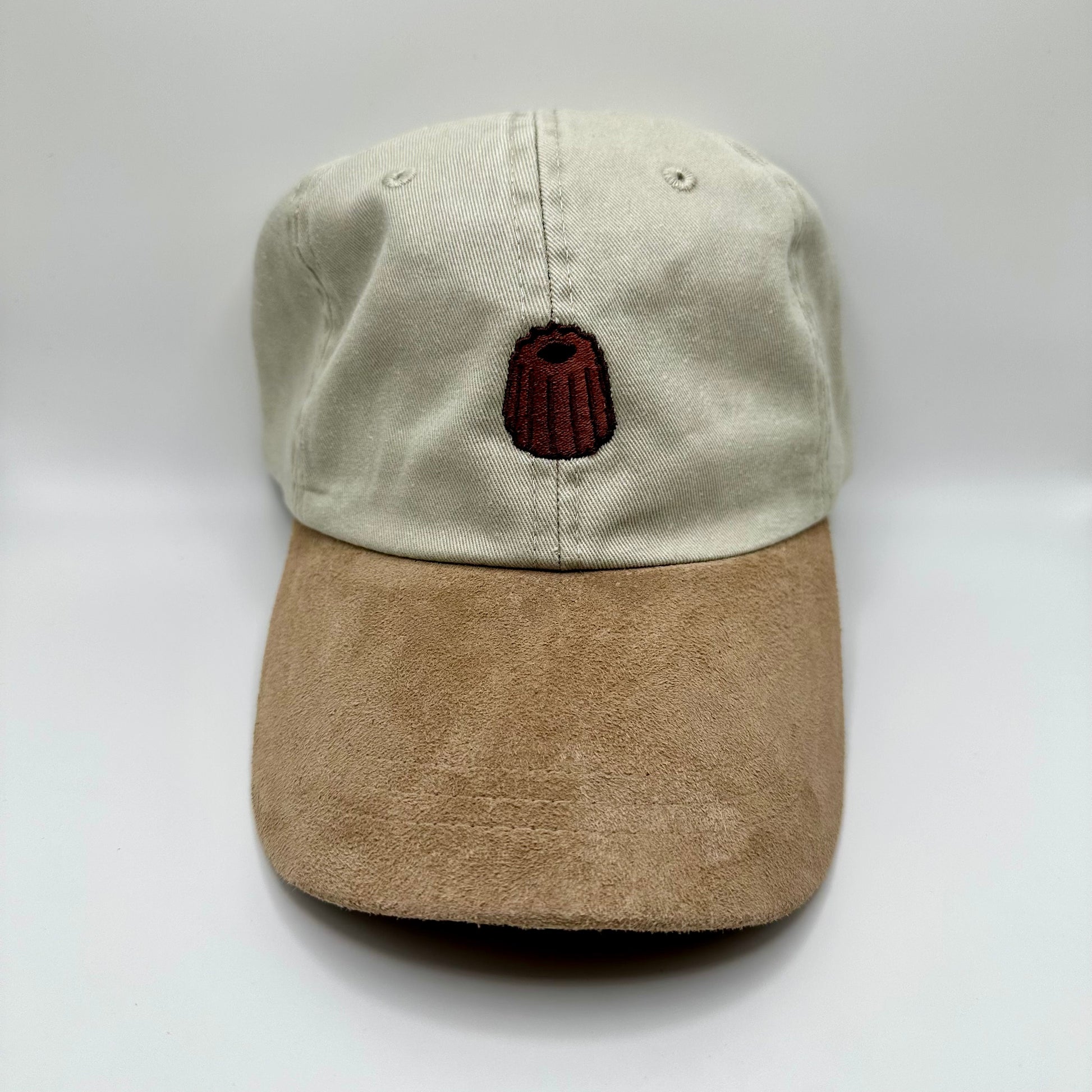 Beige Hat with suede-looking khaki bill. Canelê pastry embroidered on the top. 