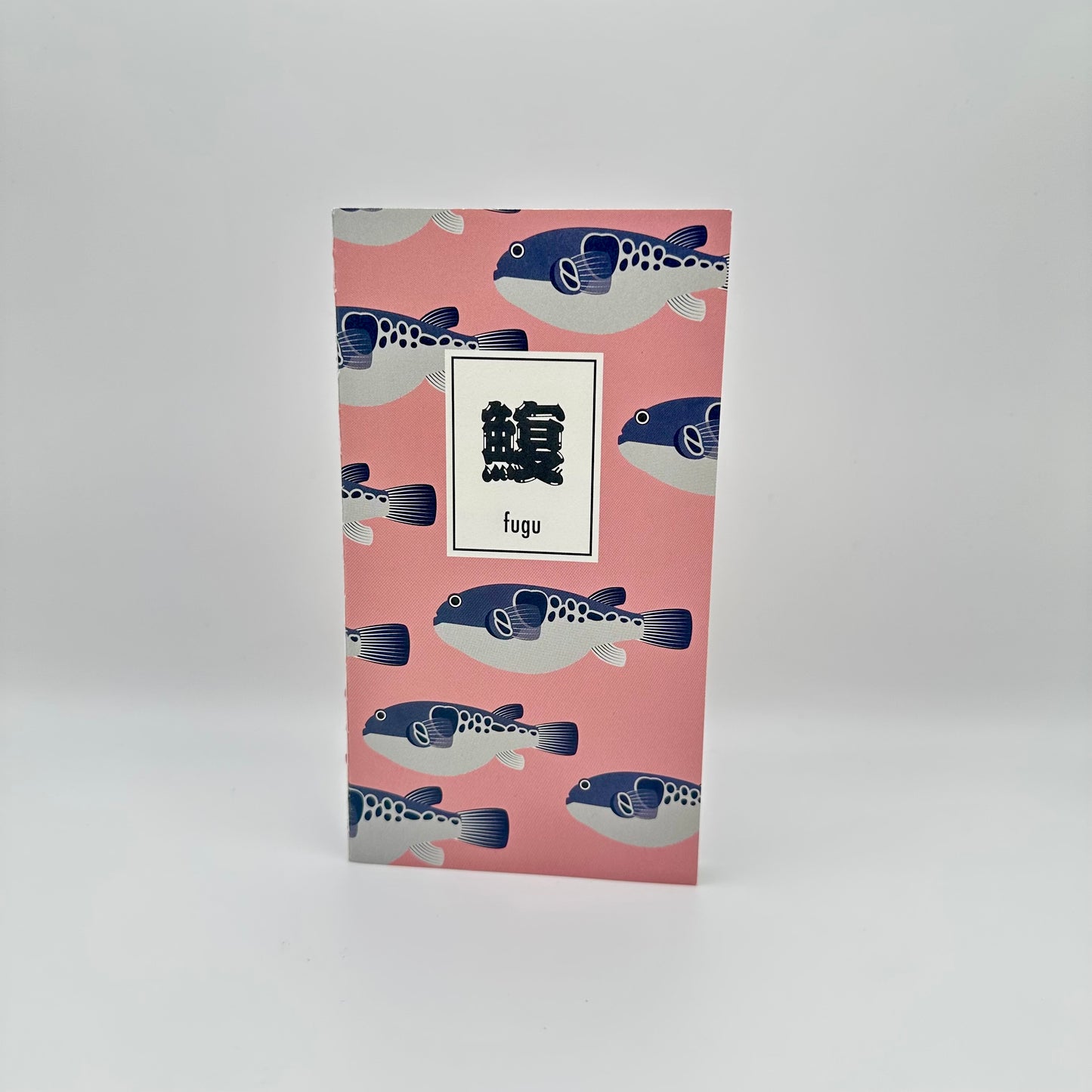 Pink notebook with blue and white blowfish on the cover. Japanese characters in the middle that read Fugu.