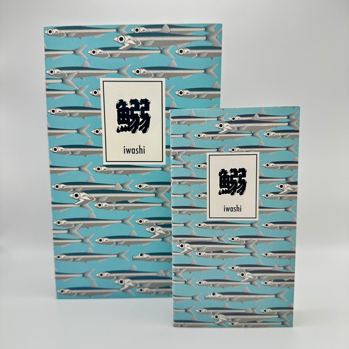 Two notebooks side by side Blue background with silver sardines swimming. Text box in Japanese that reads "Iwashi"