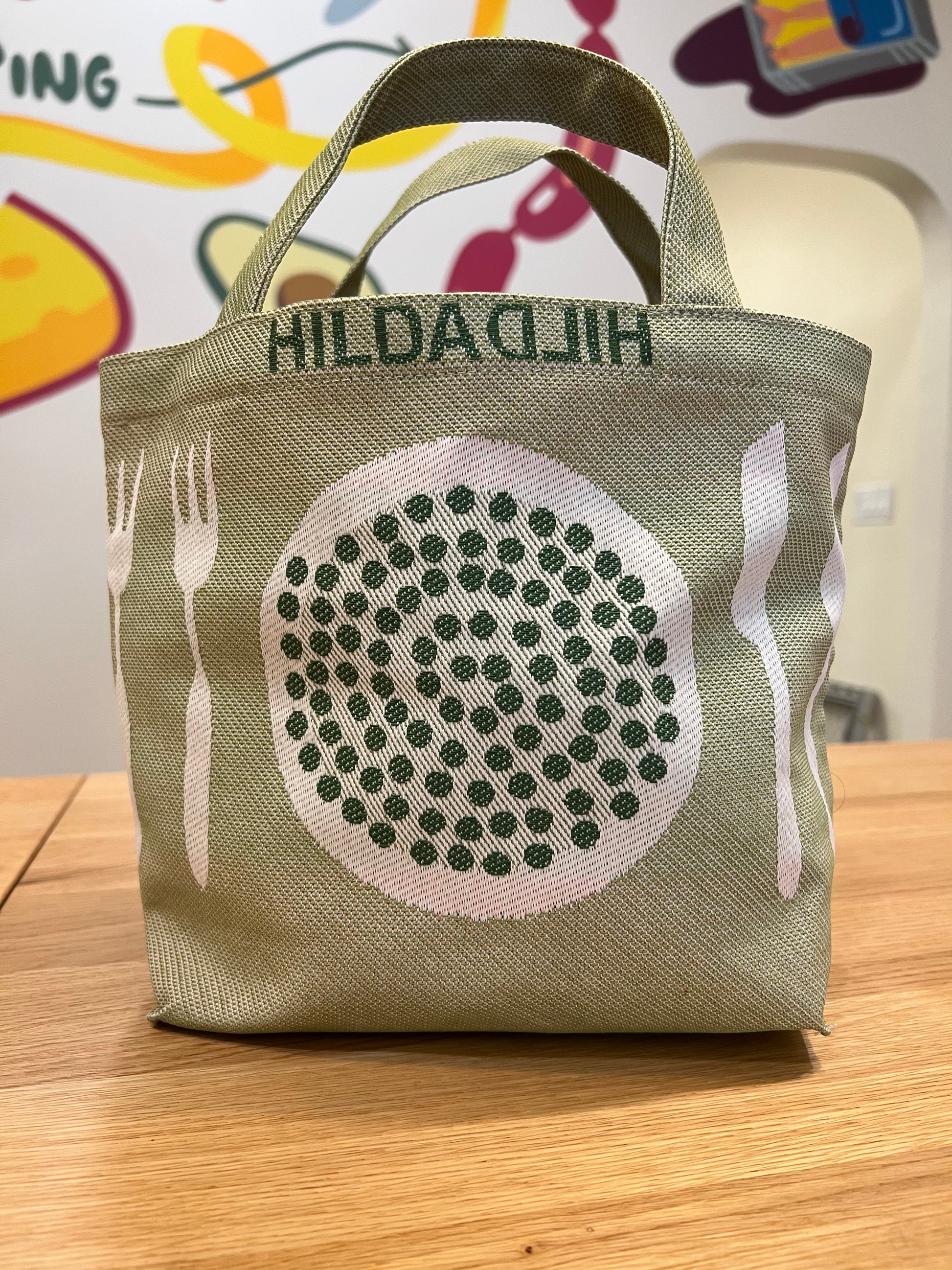 Hilda Hilda lunch bag showing the opposite side which has peas/beans on a plate with eating utensils.