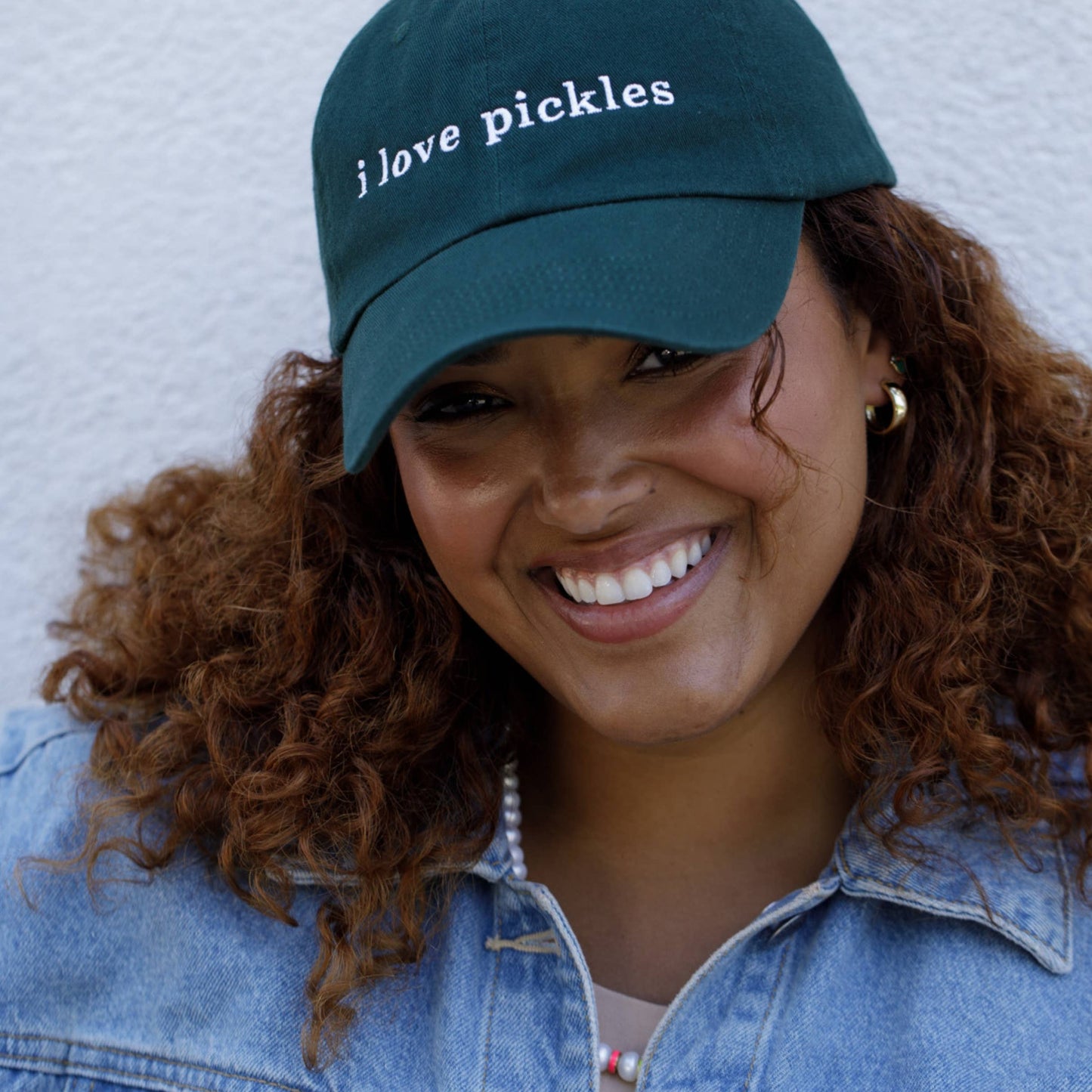 Person wearing a green cap with 'i love pickles' text against a white background