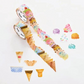 Colorful ice cream themed stickers with colorful scoops of ice cream and assorted ice cream cups and cones. Stickers overlap on a roll.