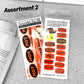 Two packages of suggestive stickers on a textured surface with 'Assortment 2' text.