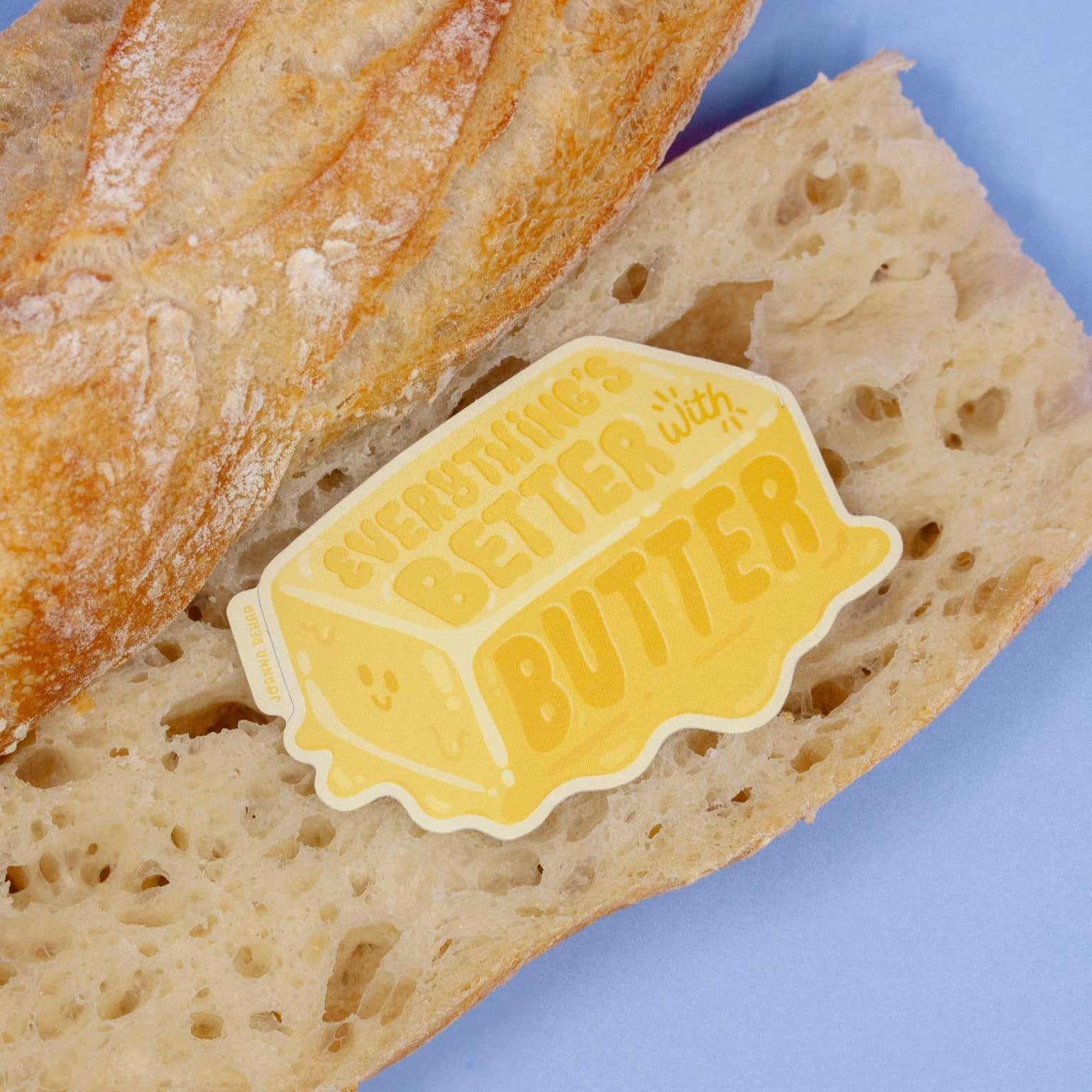 Butter sticker staged on a real baguette that is sliced. The sticker reads: Everything's better with butter.