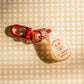 Decorative zipper charm shaped like a red and white Kewpie Mayo bottle. Text reads "kewtie baby... 100% adorable." Red clasp and hardware.