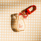 Back view -- Decorative zipper charm shaped like a red and white Kewpie Mayo bottle. Text reads "i'm fuckin' cute." Red clasp and hardware.