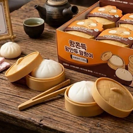 Steamed buns in a yellow steamer with a box of bao bun squishies on a wooden table.