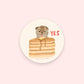 round sticker with illustrated cat licking pad of butter on a stack of pancakes and text just reads "yes" 
