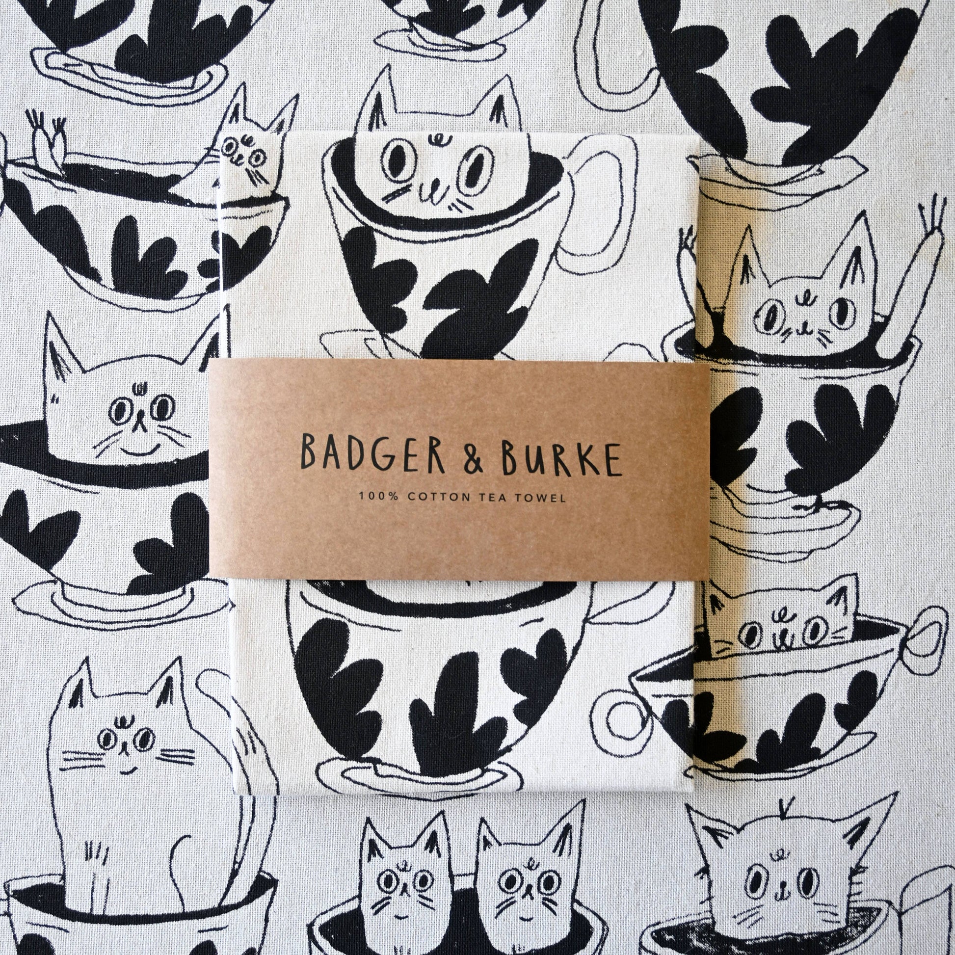 Cotton tea towel with black and white cat and teacup design, branded 'Badger & Burke'.