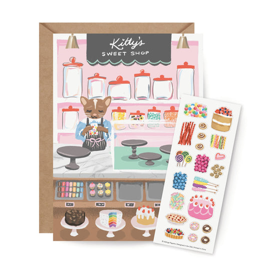 Interactive Card that includes stickers so one can decorate the front of the Sweet Shop with cakes and sweets. Text reads Kitty's Sweet Shop.