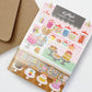 Interactive Card that includes stickers so one can decorate the front of the Sweet Shop with cakes and sweets. Text reads Kitty's Sweet Shop.