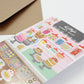 Interactive Card that includes stickers so one can decorate the front of the Sweet Shop with cakes and sweets. Text reads Kitty's Sweet Shop.
