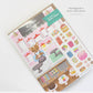 Interactive Card that includes stickers so one can decorate the front of the Sweet Shop with cakes and sweets. Text reads Kitty's Sweet Shop. Text that says: Packaged in a clear cello sleeve.