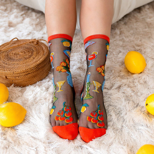 Person wearing sheer socks with colorful designs on a fluffy white surface with lemons.