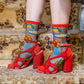 Red high-heeled shoes with colorful designs worn on patterned carpet
