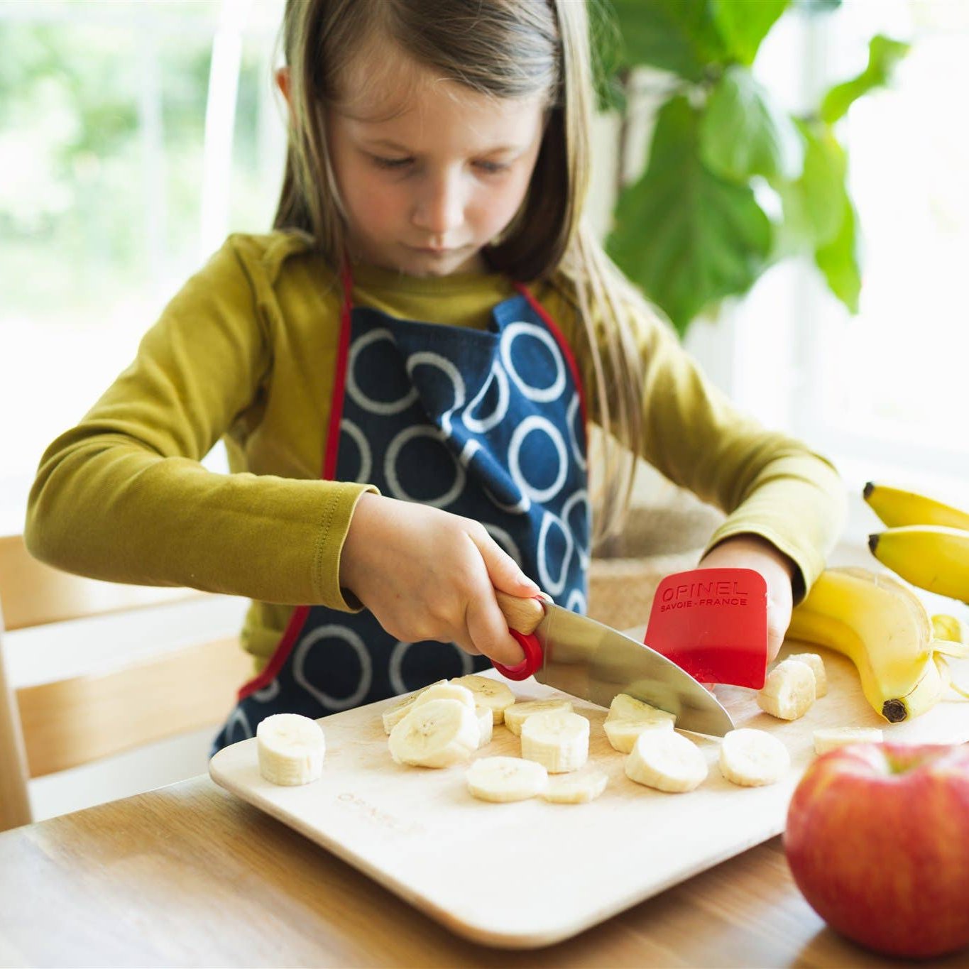 Photo of child cutting bananas with knife and finger guard.