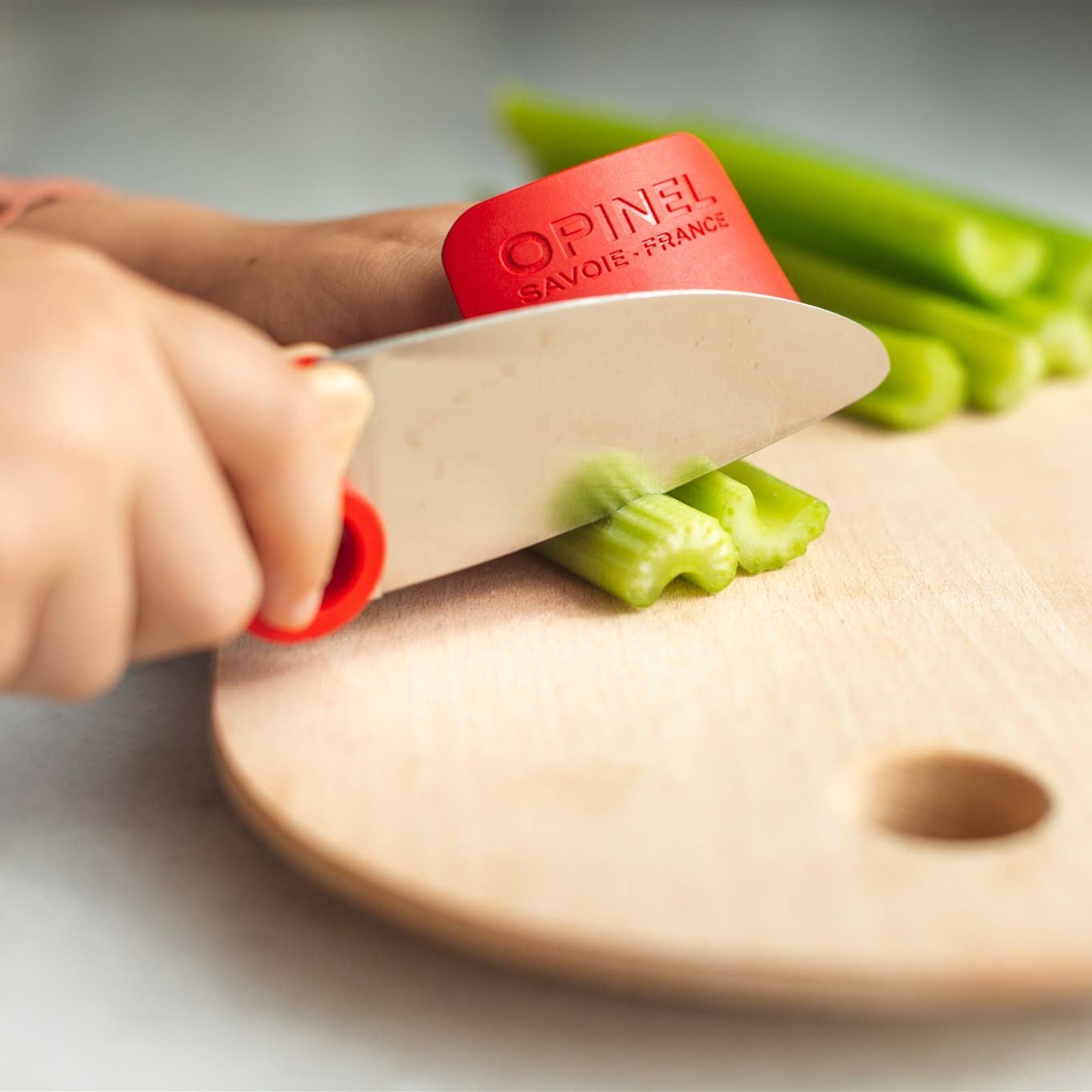 Photo of child cutting celery with knife and finger guard.