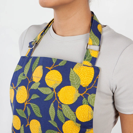Person wearing a blue apron with lemon pattern on a white background