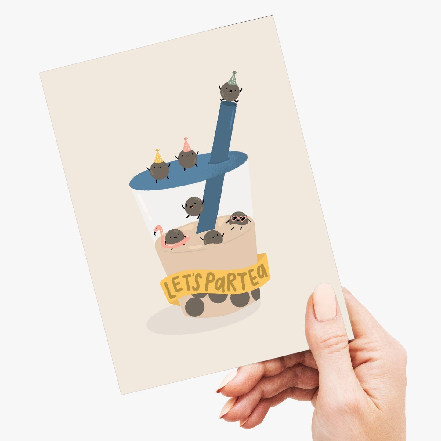 A hand holding a cream-colored greeting card featuring a cute illustration of small hedgehogs in a bubble tea cup with the text 'LET'S PART TEA'.