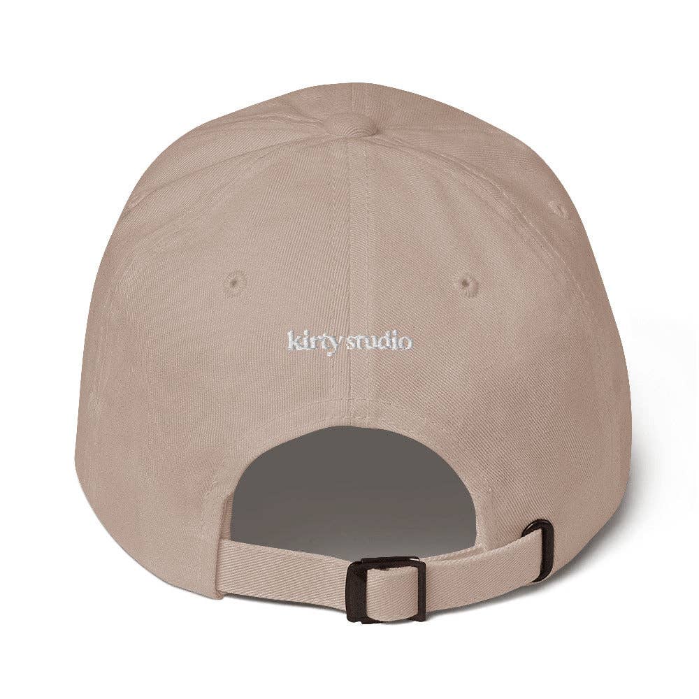Beige cap with 'kirty studio' embroidered on the back against a white background