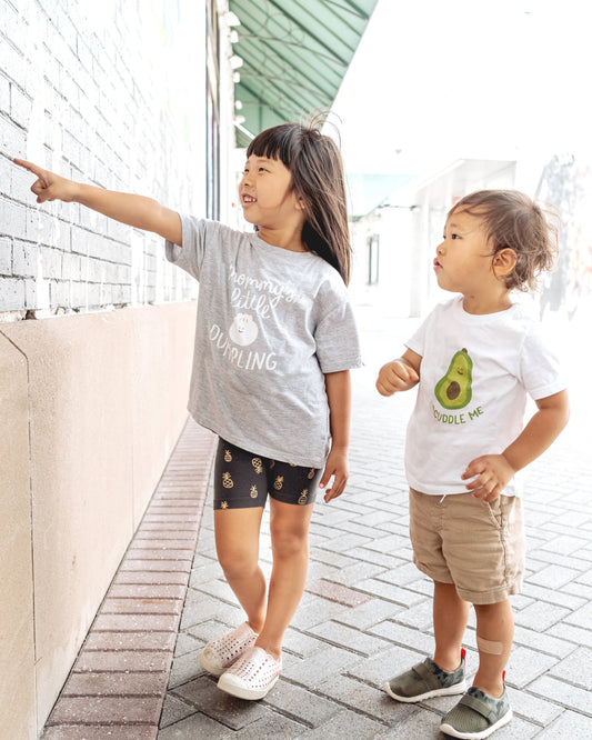 Two kids modeling shirts. One with a dumpling on it, the other with an avocado.