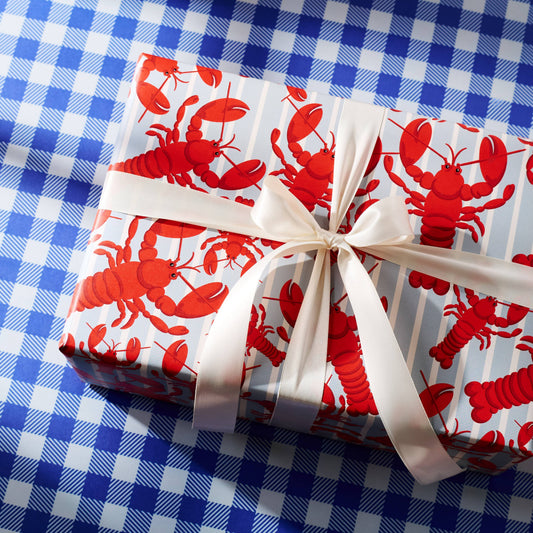 Gift wrapped in red lobster patterned paper with a white ribbon on a blue checkered background