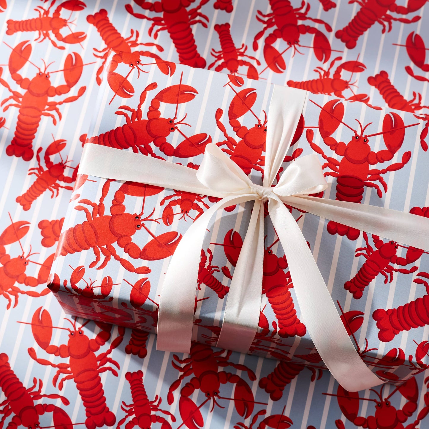 Gift wrapped in red lobster patterned paper with a white ribbon.