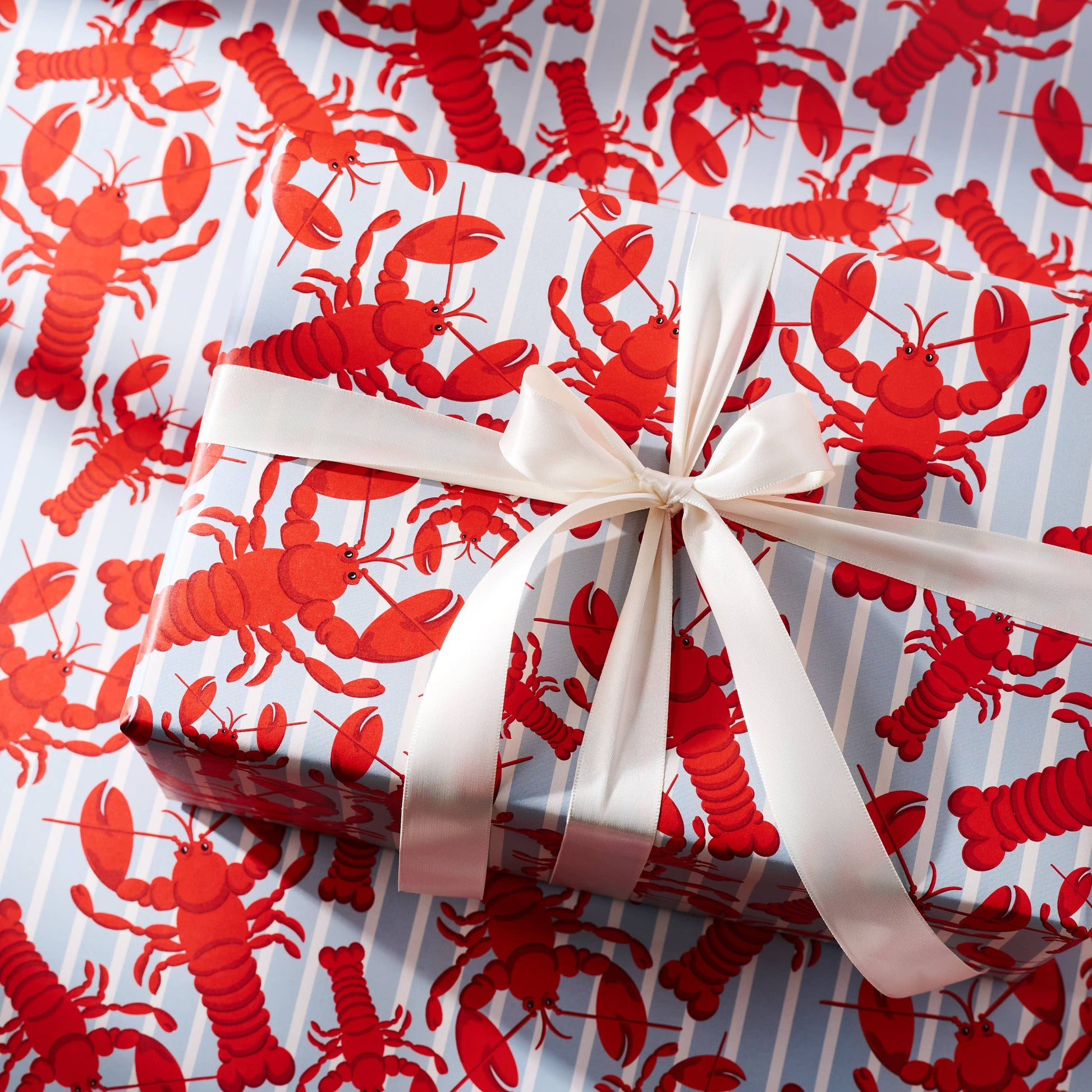 Gift wrapped in red lobster patterned paper with a white ribbon.