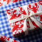 gift wrapped in lobster wrapping paper. Gift wrap is double sided, one with red lobsters and the other with blue gingham 