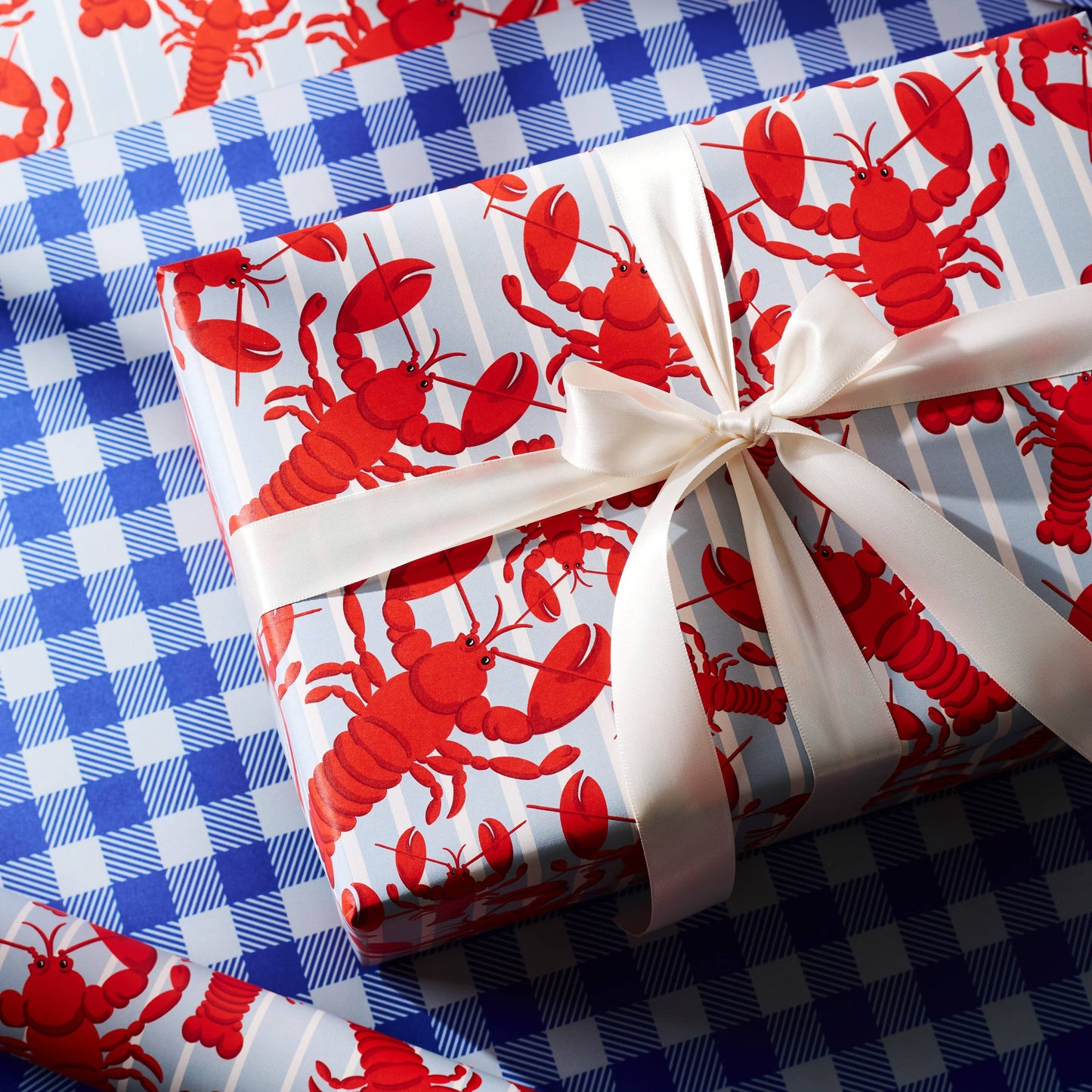 gift wrapped in lobster wrapping paper. Gift wrap is double sided, one with red lobsters and the other with blue gingham 