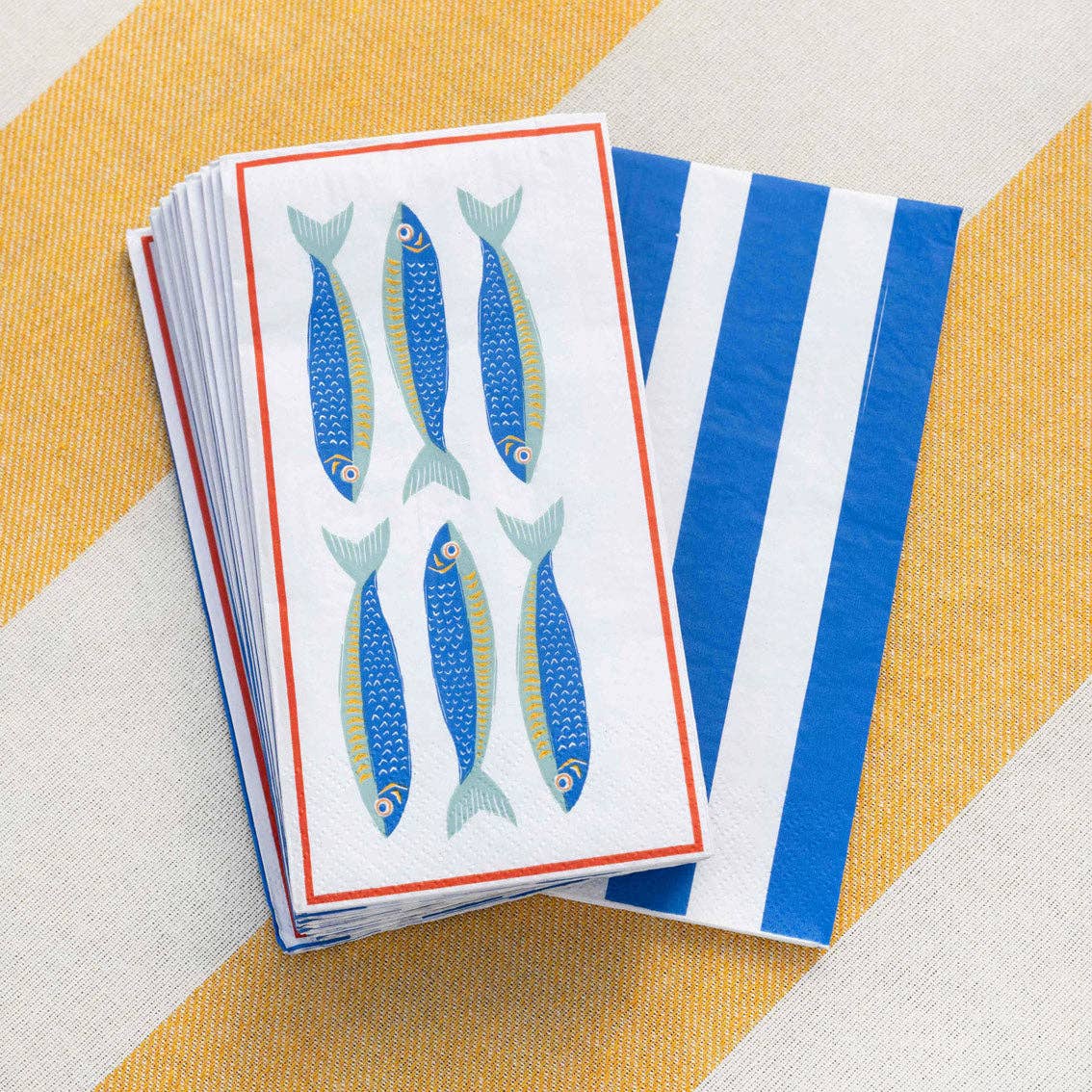 Stack of paper napkins with fish design on a striped yellow and white background