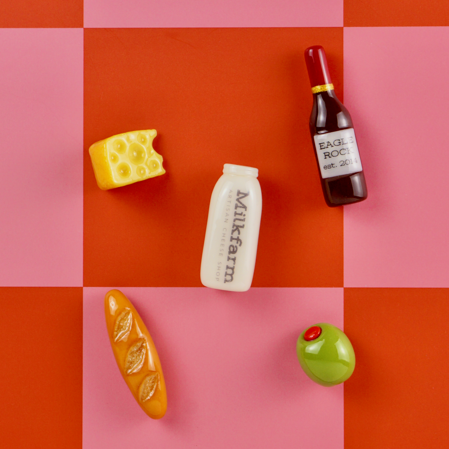 Various food product magnets on a checkered red and pink background.