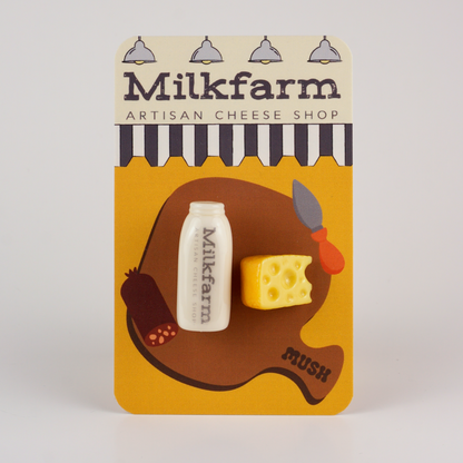 Milkfarm cheese shop packaging with a bottle and cheese magnets on a yellow background